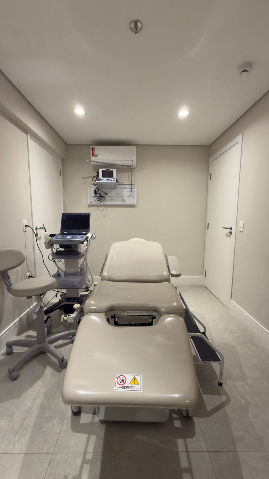 Sala de procedimentos para ablação de tireoide com maca, ultrassom e monitor de sinais vitais